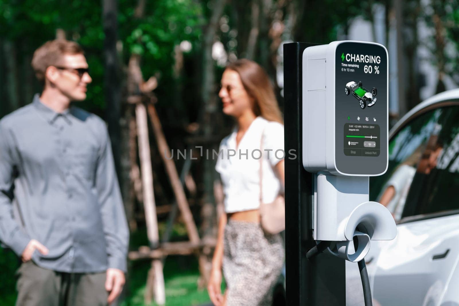 Young couple travel with EV electric car charging in green sustainable city outdoor garden in summer shows urban sustainability lifestyle by green clean rechargeable energy of electric vehicle innards