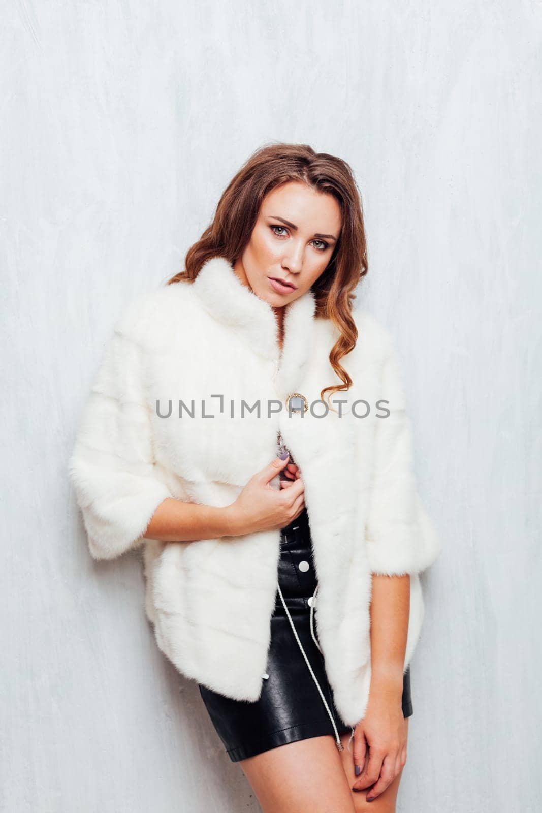 Portrait of a beautiful woman with hair curls in a white fur coat