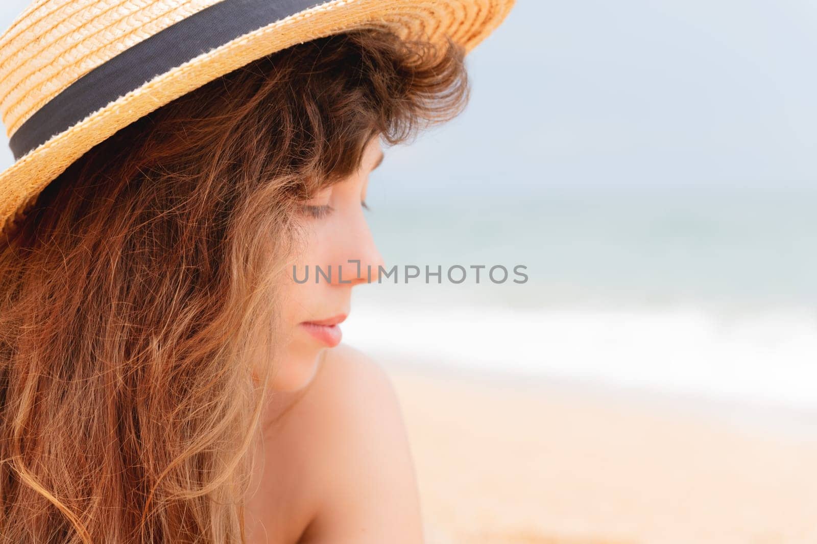 Beach woman wearing sunhat on vacation. Smiling girl looking to the side at the sea, close-up, portrait of a happy young woman.