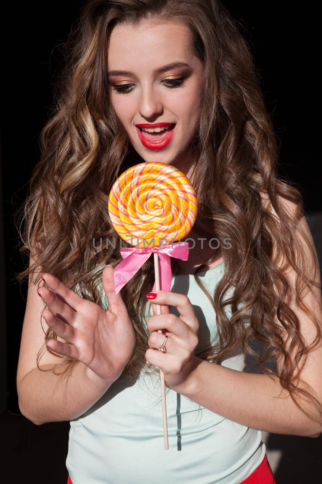 Beautiful fashionable woman eats candy big sweet lollipop by Simakov