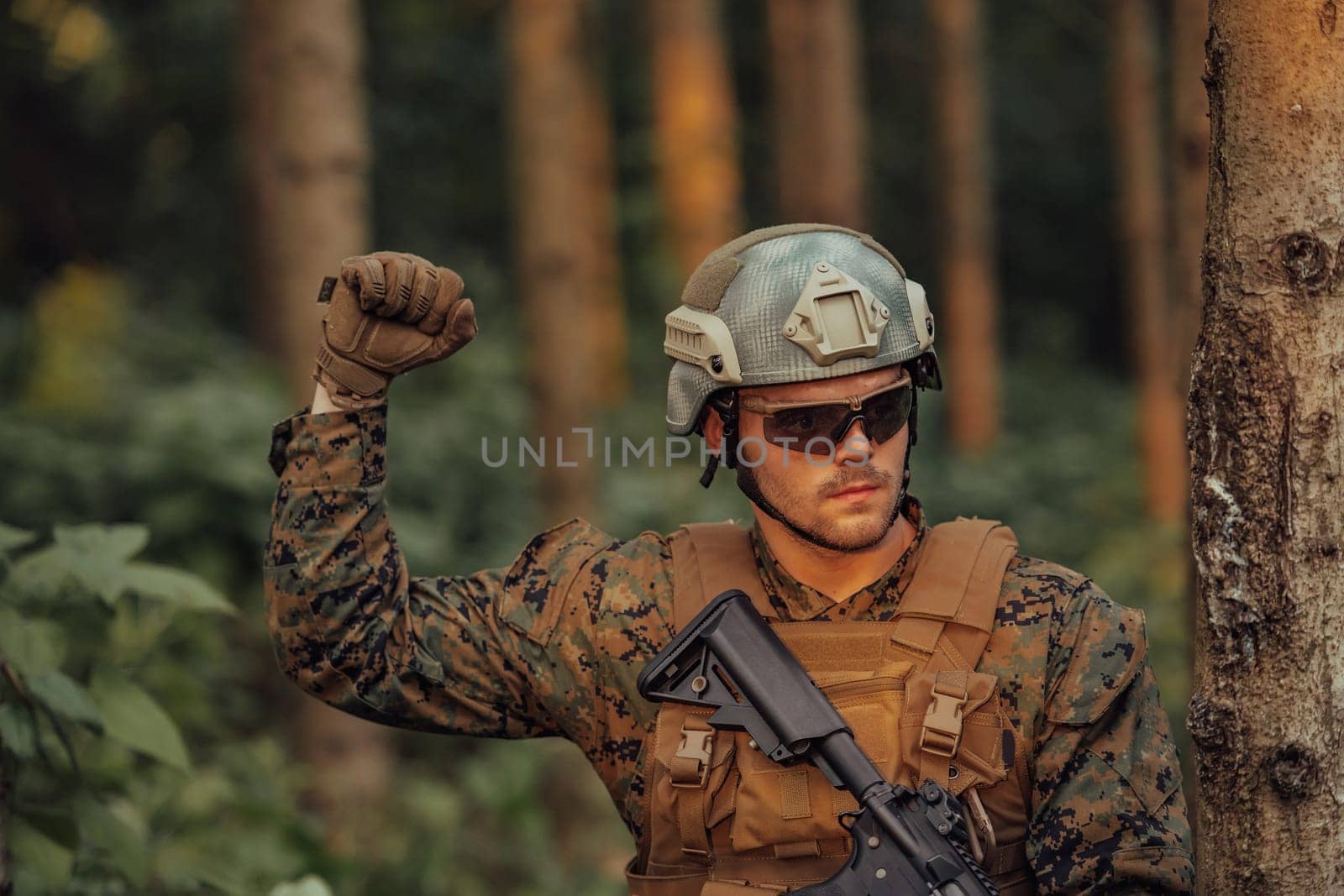 Modern warfare soldier officer is showing tactical hand signals to silently give orders and alers for squad team forest enviroment.