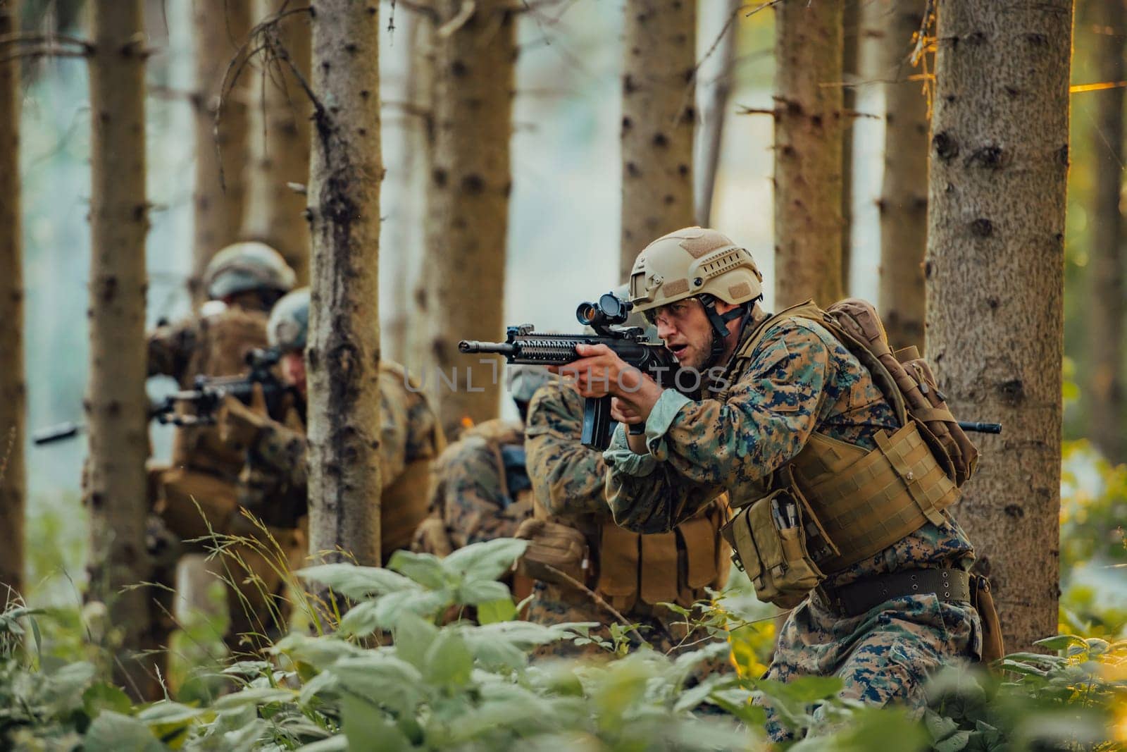 A group of modern warfare soldiers is fighting a war in dangerous remote forest areas. A group of soldiers is fighting on the enemy line with modern weapons. The concept of warfare and military conflicts.