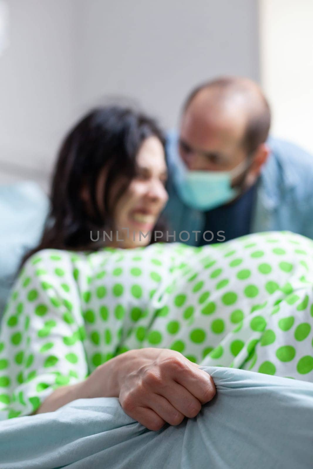 Pregnant woman trying to delivery baby in hospital ward, having husband beside her during caesarean surgery. Patient with pregnancy having paniful contractions during childbirth in maternity clinic