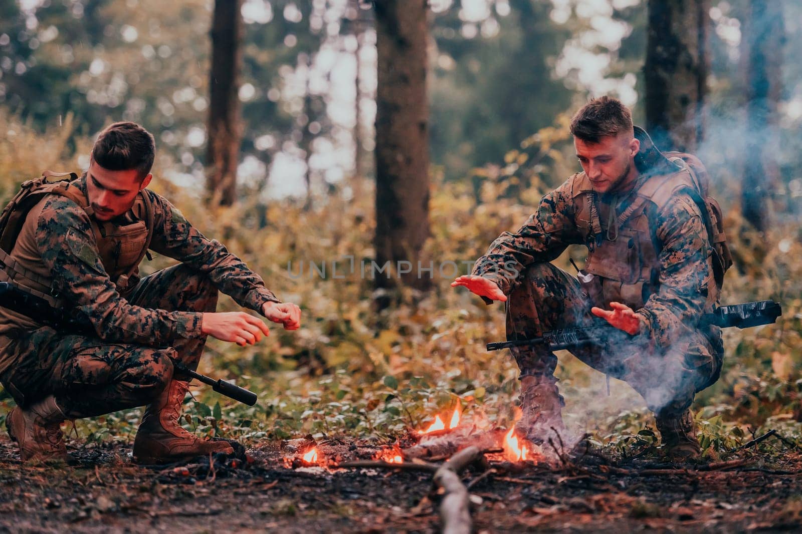 Two exhausted soldiers sitting by the fire after a weary and heavy war battle.