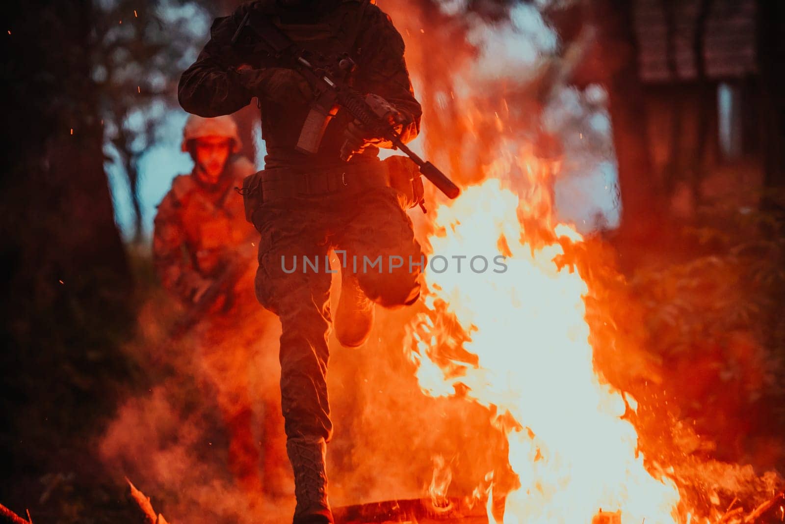 Soldier in Action at Night in the Forest Area. Night Time Military Mission jumping over fire.