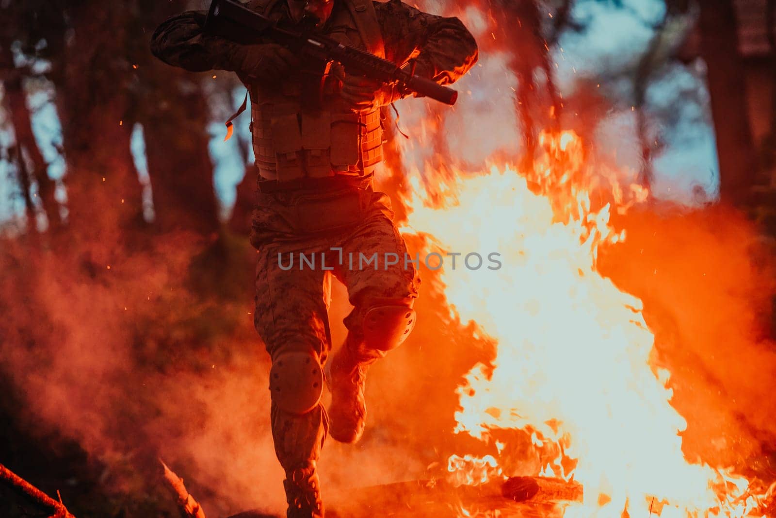 Soldier in Action at Night in the Forest Area. Night Time Military Mission jumping over fire.