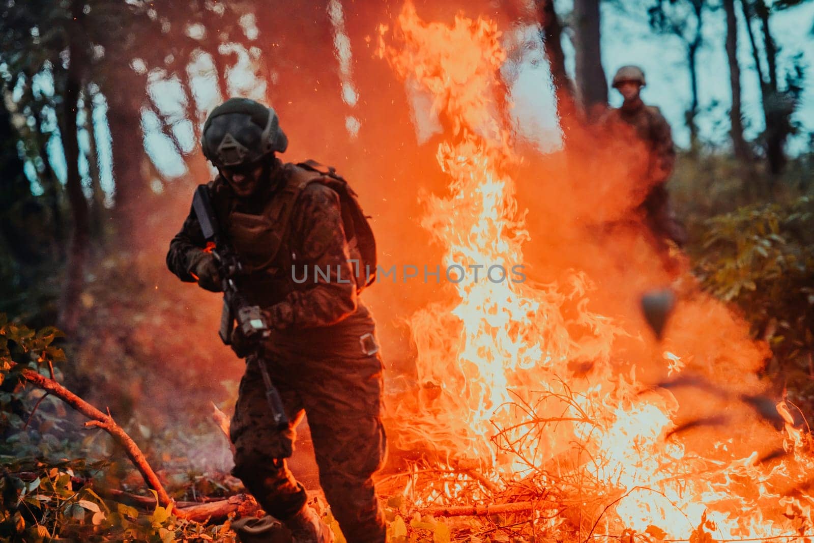 Soldier in Action at Night in the Forest Area. Night Time Military Mission jumping over fire.