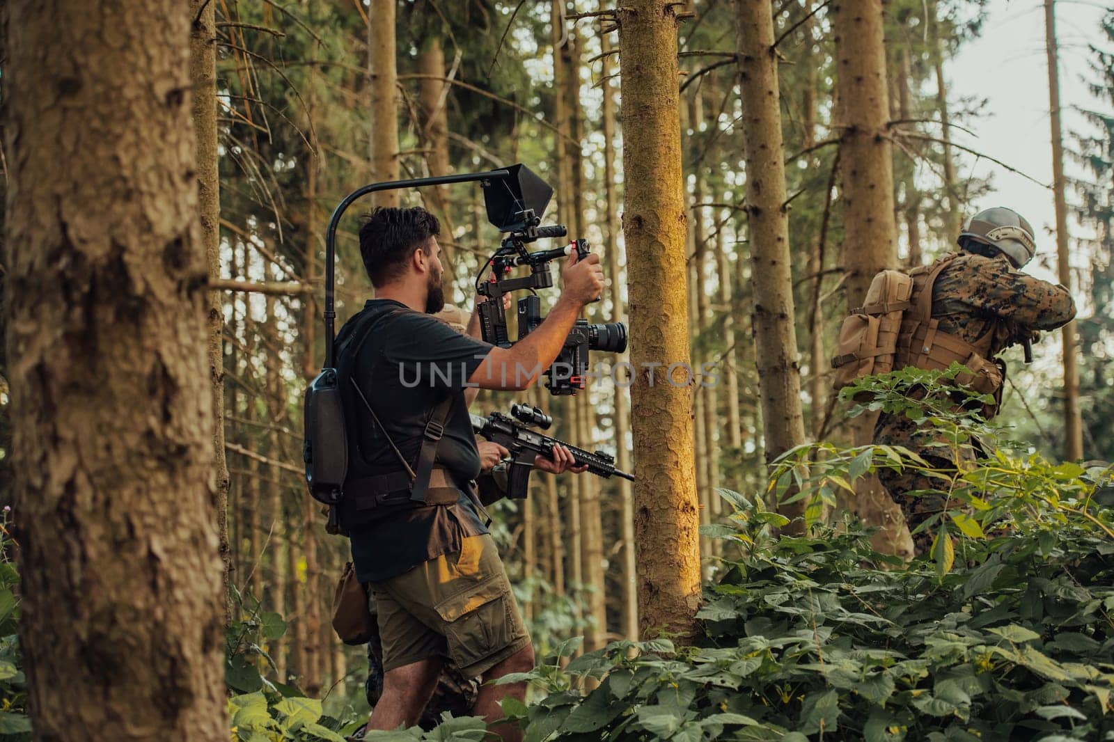 Videographer with Professional Movie Video Camera Gimbal Stabilizing Equipment Taking Action Shoot of Soldiers in Action in Forest by dotshock