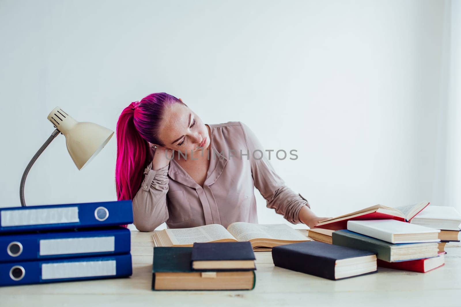 girl with Crimson hair sitting at a table reading a book