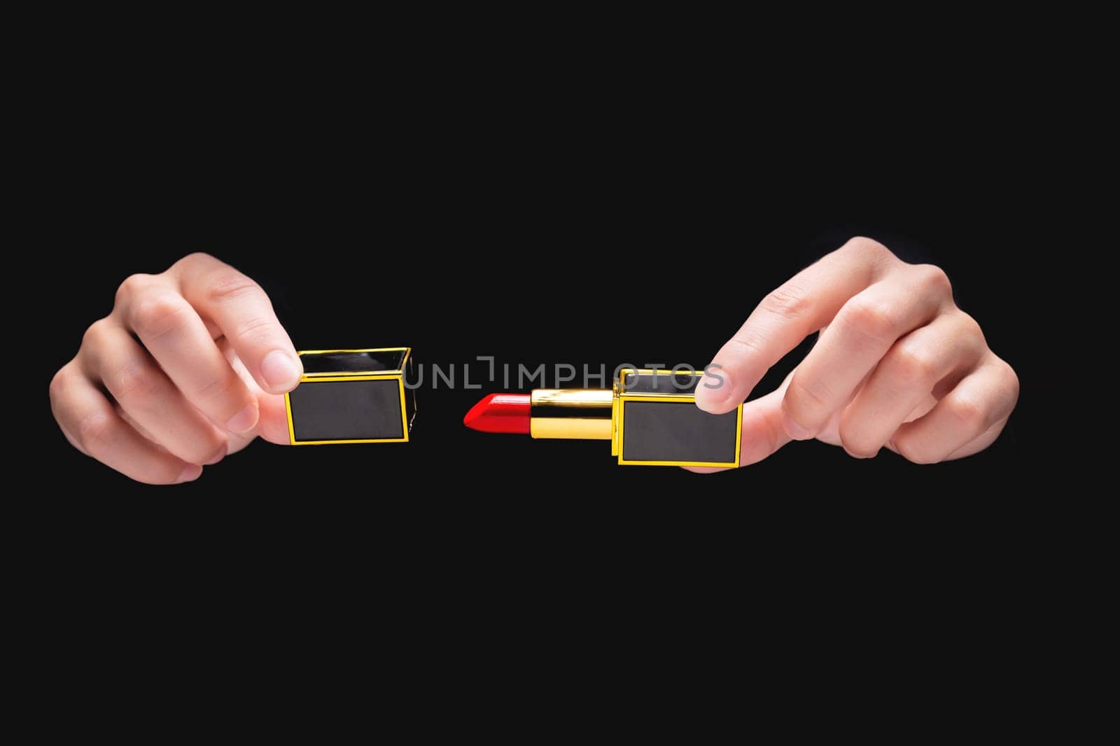 Unrecognizable woman showing bright red lipstick on black background in studio. Female hands from the dark open a tube of red lipstick and show it to the camera by yanik88