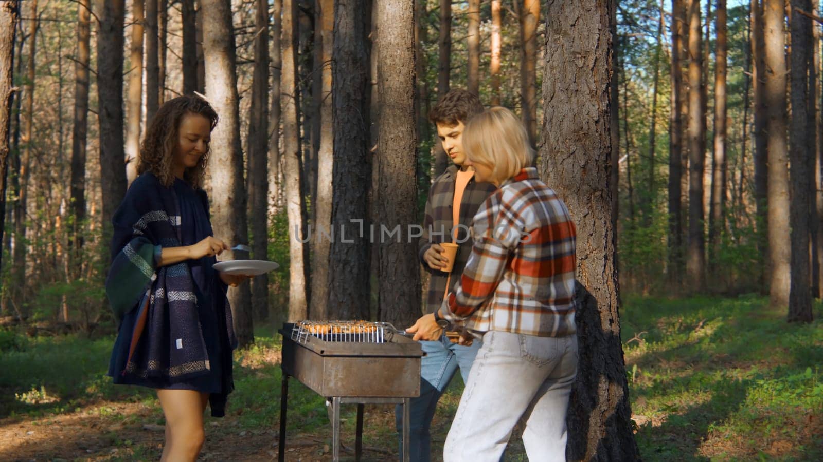 Friends cook grilled meat in forest in summer. Stock footage. Beautiful friends are relaxing in nature with barbecue in forest. Relaxing with friends in nature with barbecue on sunny summer day by Mediawhalestock