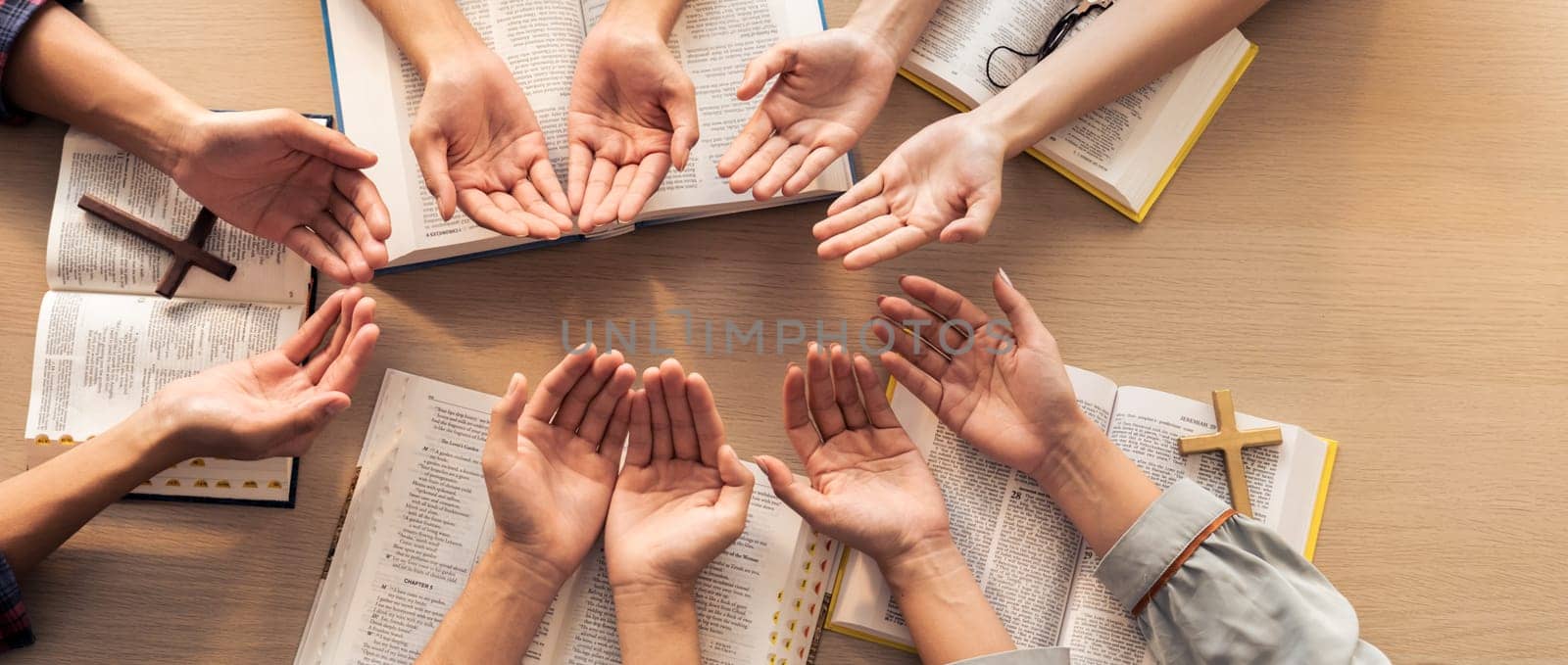 Cropped image of diversity people hand praying together at wooden church on bible book. Group of believer hold hand together faithfully. Concept of hope, religion, faith, god blessing. Burgeoning.