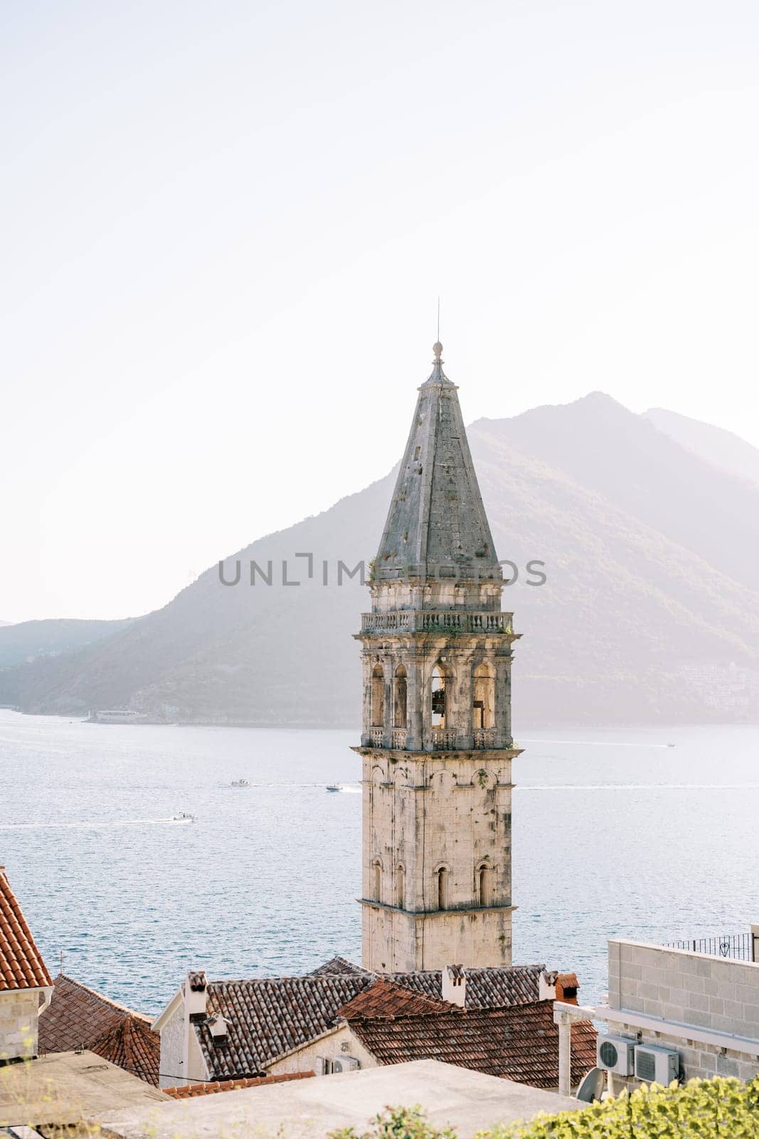 Tall ancient bell tower of the Church of St. Nicholas against the backdrop of the sea. Perast, Montenegro. High quality photo