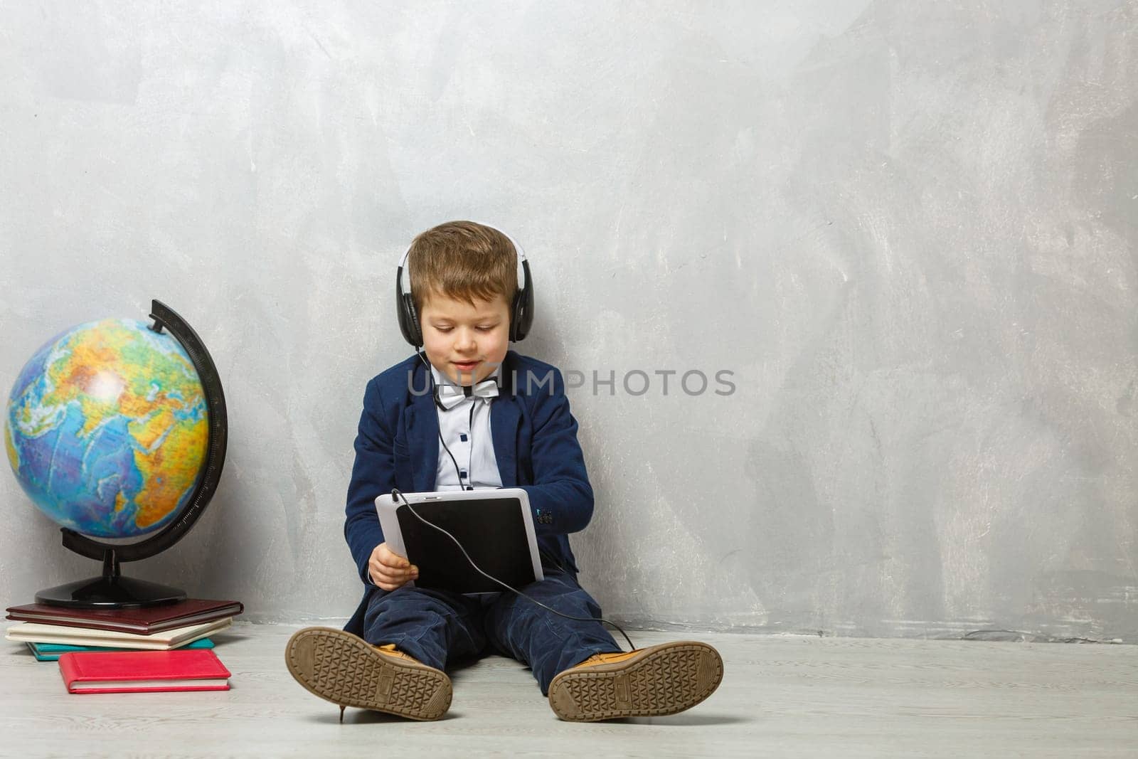 Cheerful little boy holding digital tablet against gray background. School concept. Back to School.