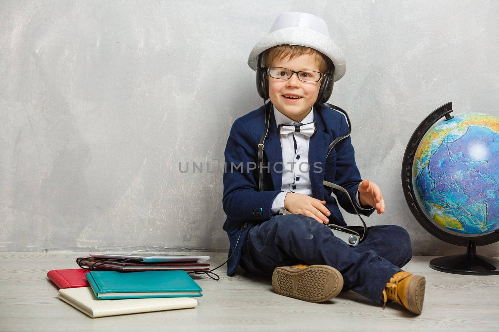 schoolboy with headphones on gray background.