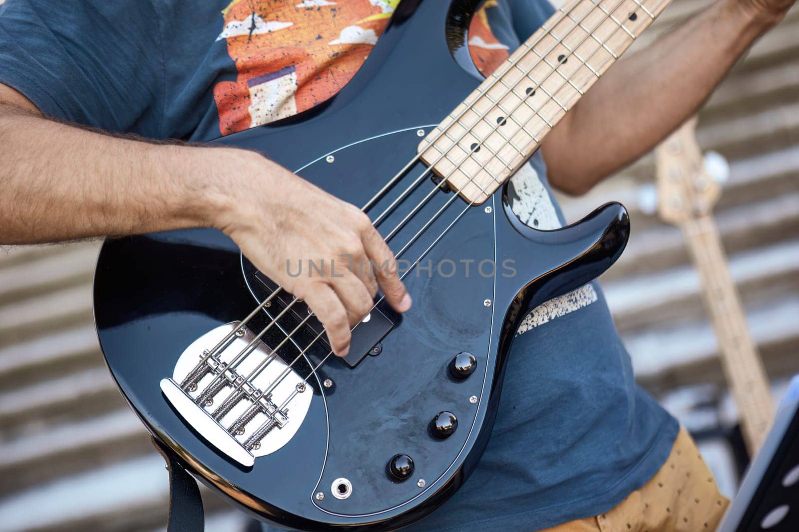 Close-up of a musician's hands playing the guitar during a live daylight performance.