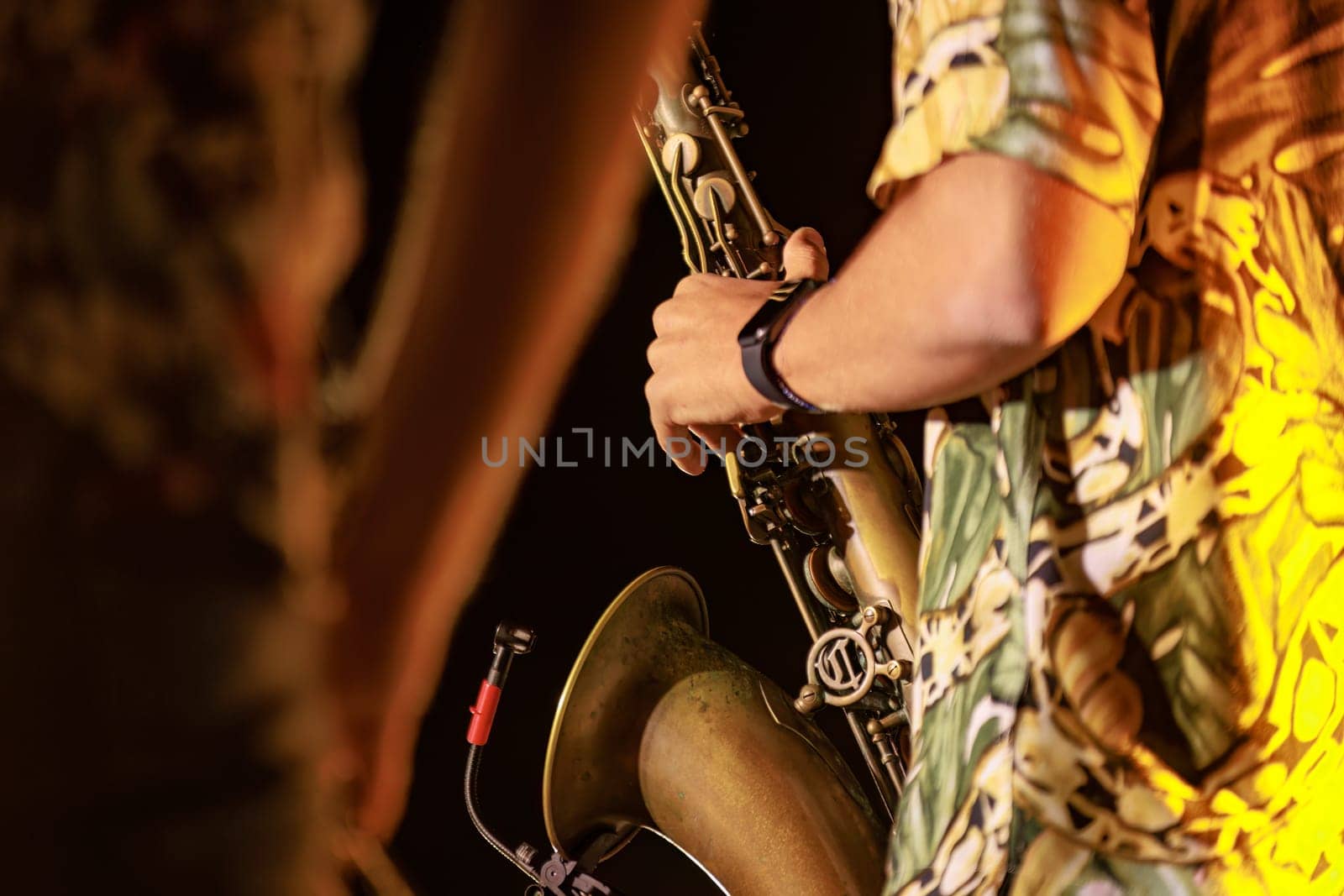 Close-up of a musician's hands playing the trumpet during a vibrant live performance at night