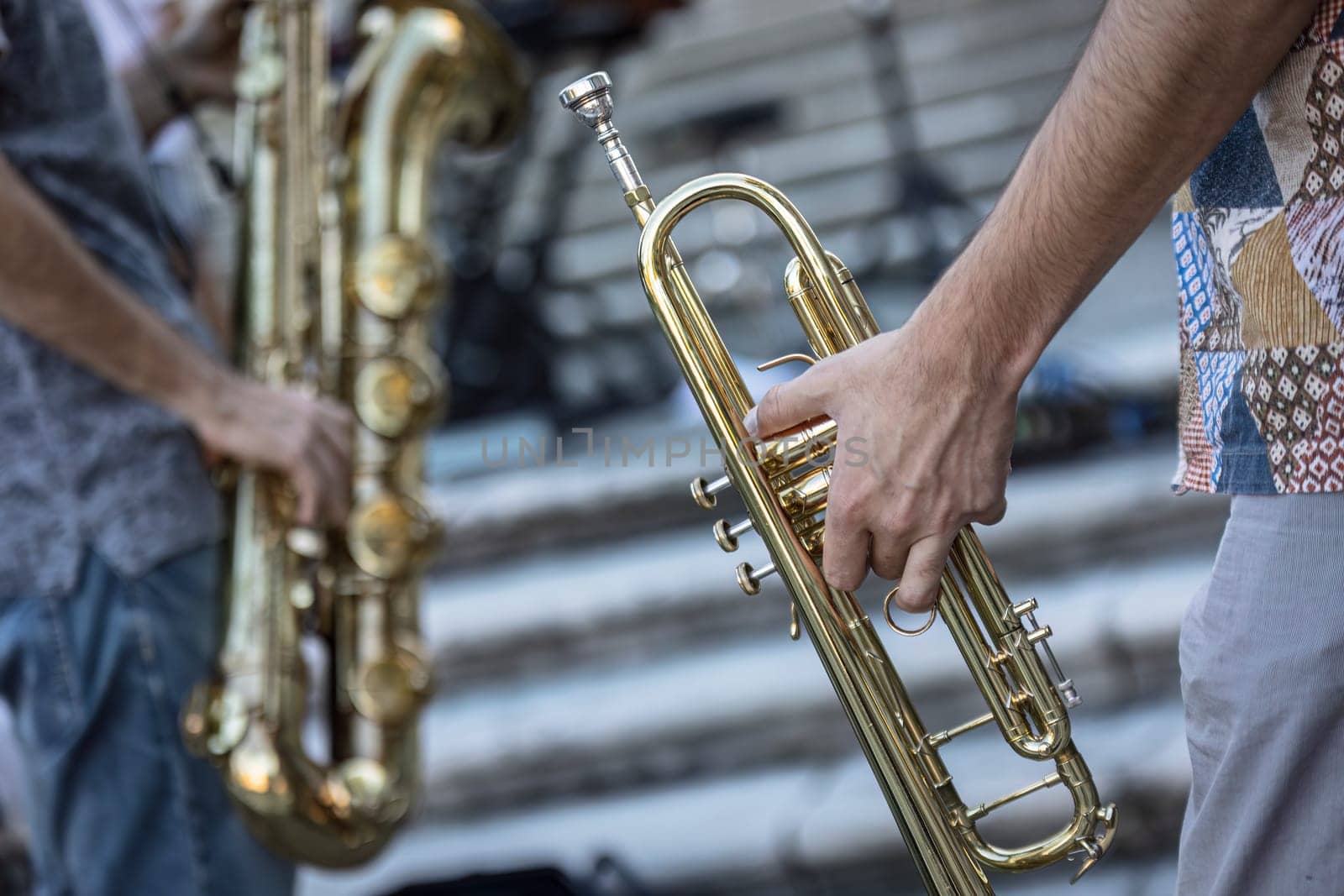 Close-up of a musician's hands playing the trumpet during a vibrant live performance in daylight.