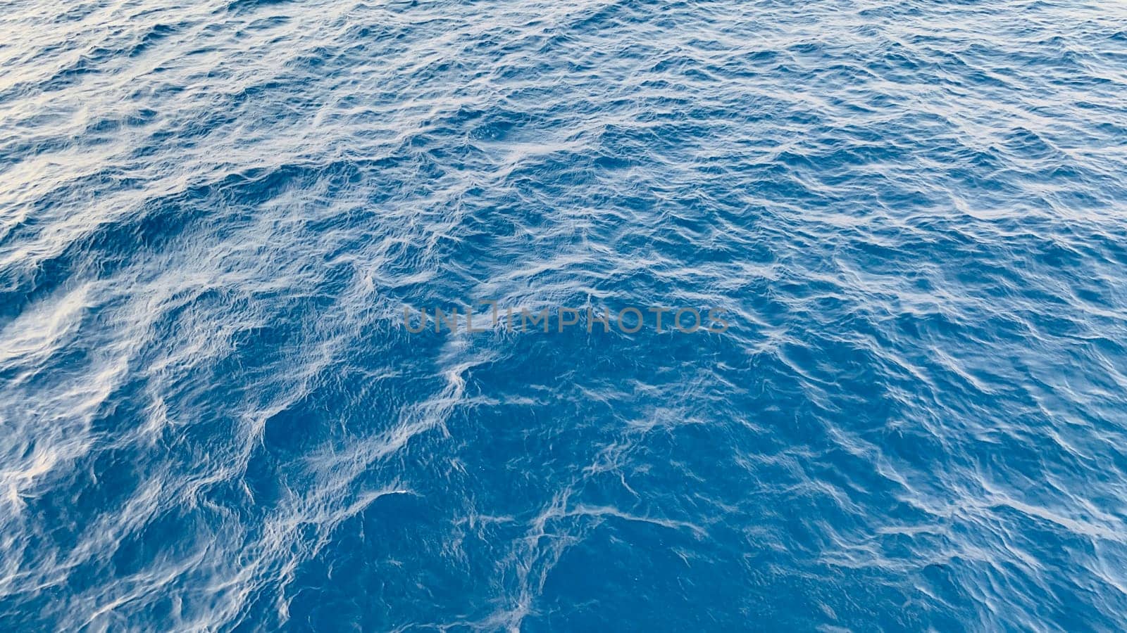 Photo of abstract blue color water wave, pure natural swirl pattern texture, background photography, Blue ocean water texture background. Surface of the sea in bali indonesia