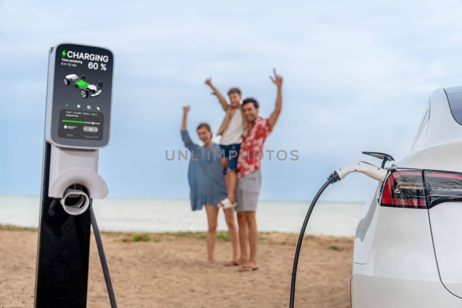 Alternative family vacation trip traveling by the beach with electric car recharging battery from EV charging station with blurred cheerful and happy family enjoying the seascape background. Perpetual