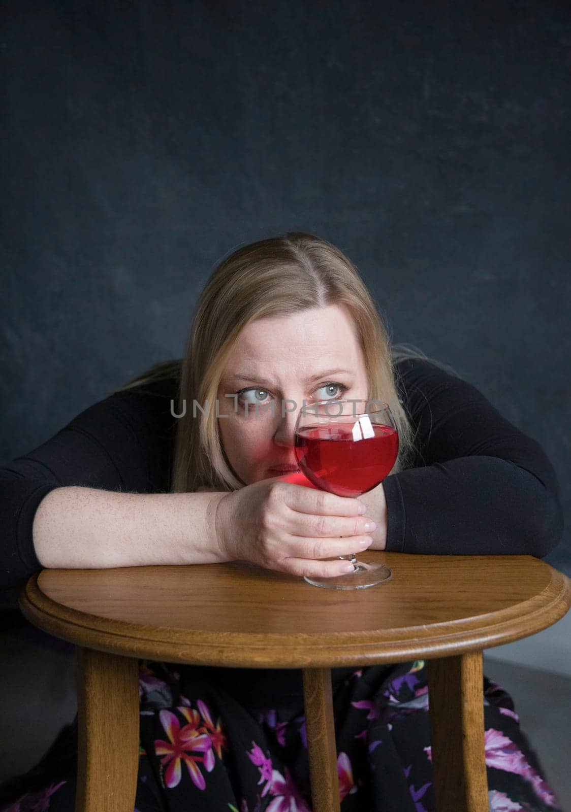 portrait of a depressed middle aged woman sitting alone at a table and holding glasses of red wine in her hand, burnout and depression concept, High quality photo