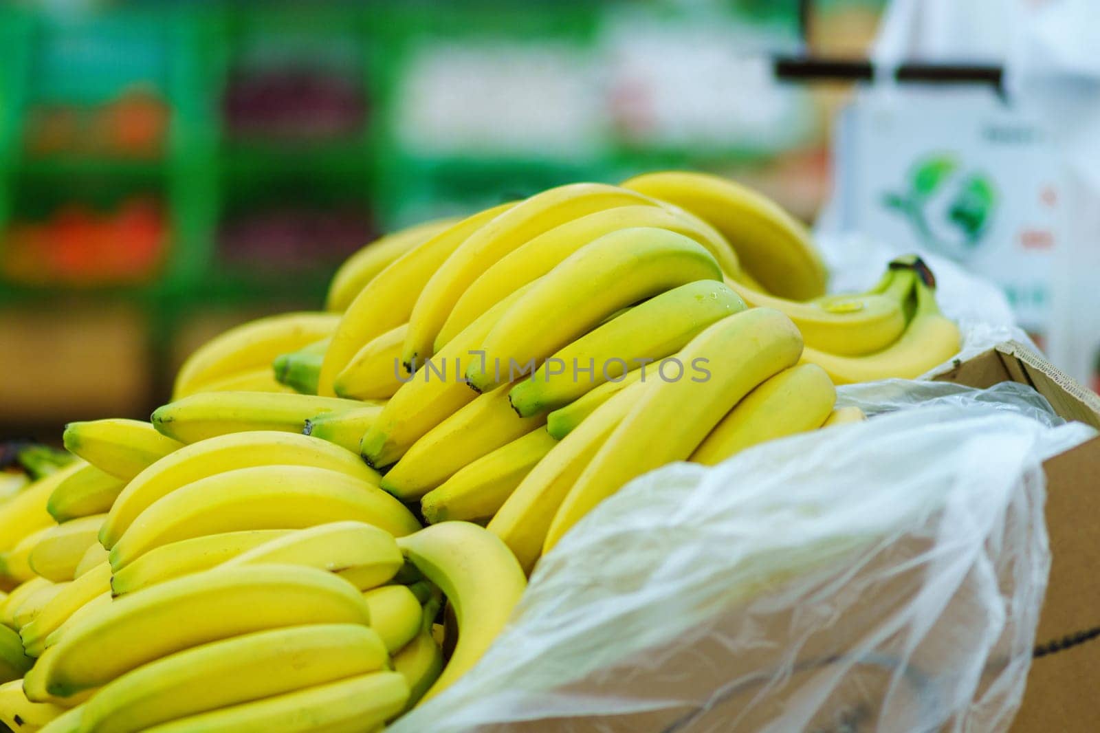 Clusters of yellow ripe bananas in a store laid out in rows in close-up. Select focus