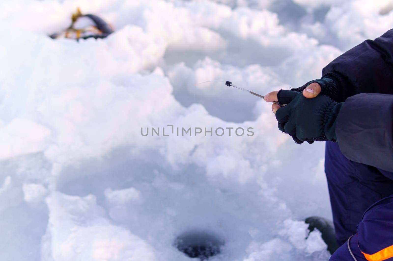 Person holding a small fishing rod in the snow. Selective focus. Copy space