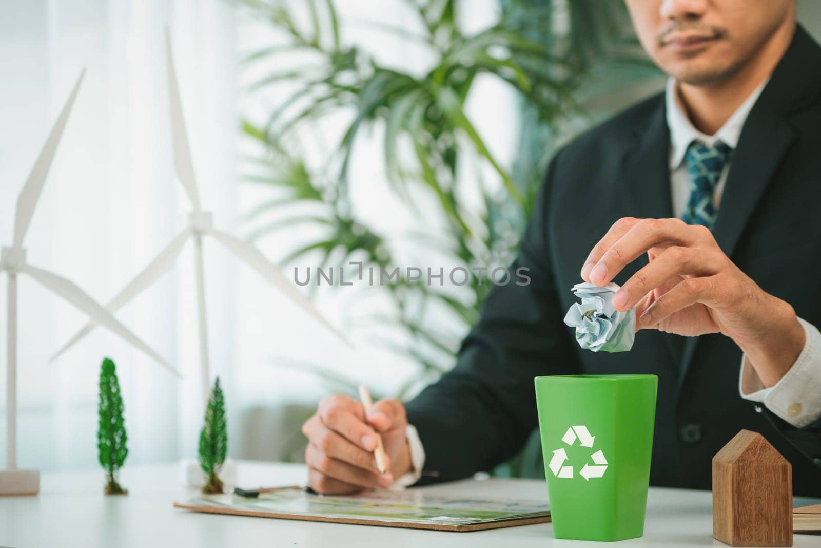 Businessman put paper waste on small tiny recycle bin in his office symbolize corporate effort on eco-friendly waste management by recycling for greener environment and zero pollution. Gyre