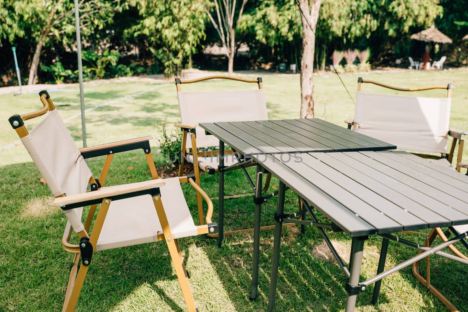 Experience the joy of outdoor camping with a tent, tables, and chairs for your summer picnic. This suburban patio setup provides comfortable seating and shade, perfect for relaxation. by Sorapop