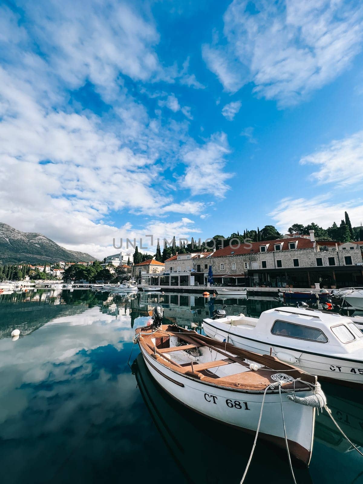 Boats are moored at the waterfront of the resort town at the foot of the mountains. High quality photo