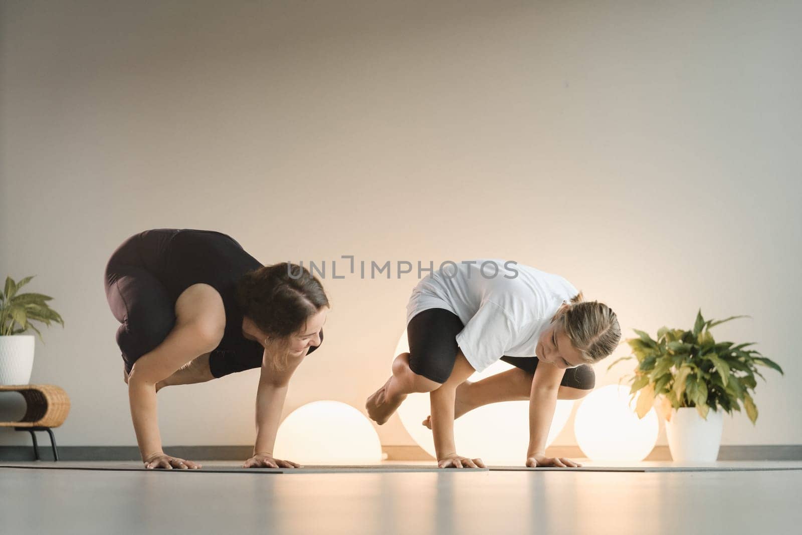 Mom and teenage daughter do gymnastics together in the fitness room. A woman and a girl train in the gym by Lobachad