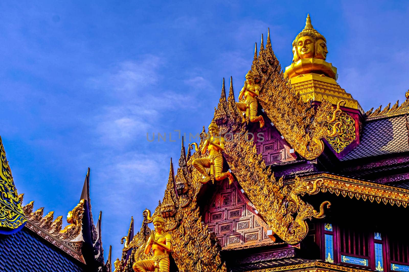 Traditional Thai Style Animal Gods Carved on Roof Decorations Against a Blue Sky