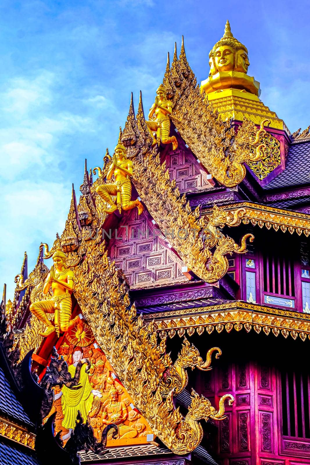 Traditional Thai Style Animal Gods Carved on Roof Decorations Against a Blue Sky