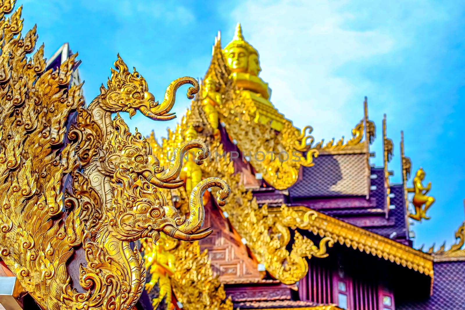 Traditional Thai Style Animal Gods Carved on Roof Decorations Against a Blue Sky