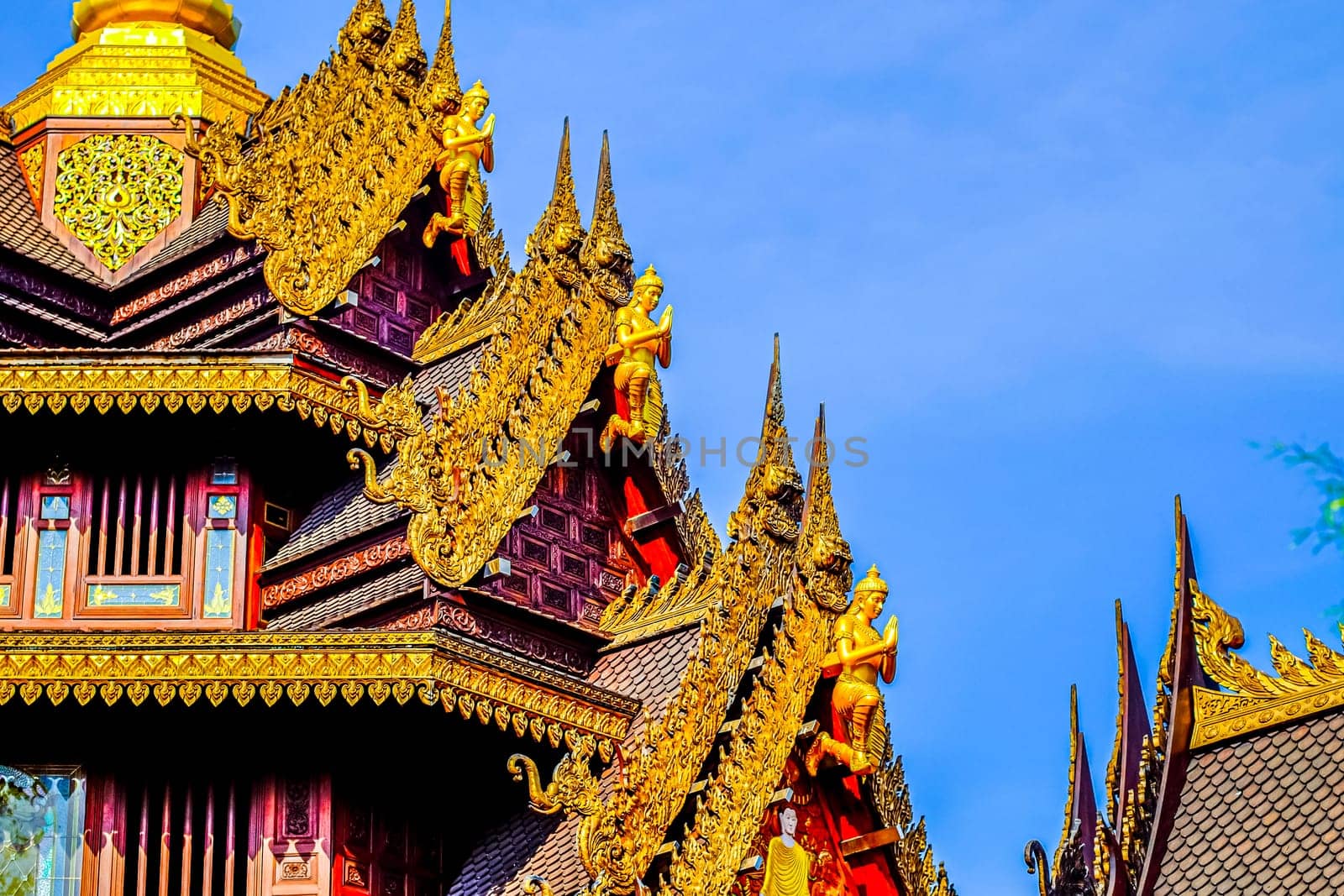 Traditional Thai Style Animal Gods Carved on Roof Decorations Against a Blue Sky