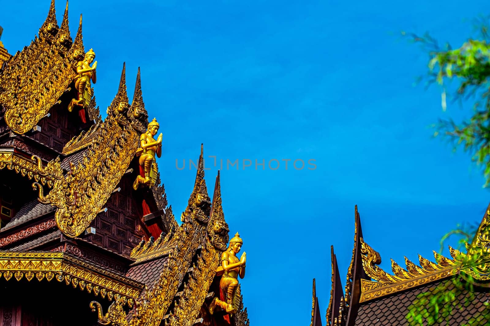 Traditional Thai Style Animal Gods Carved on Roof Decorations Against a Blue Sky
