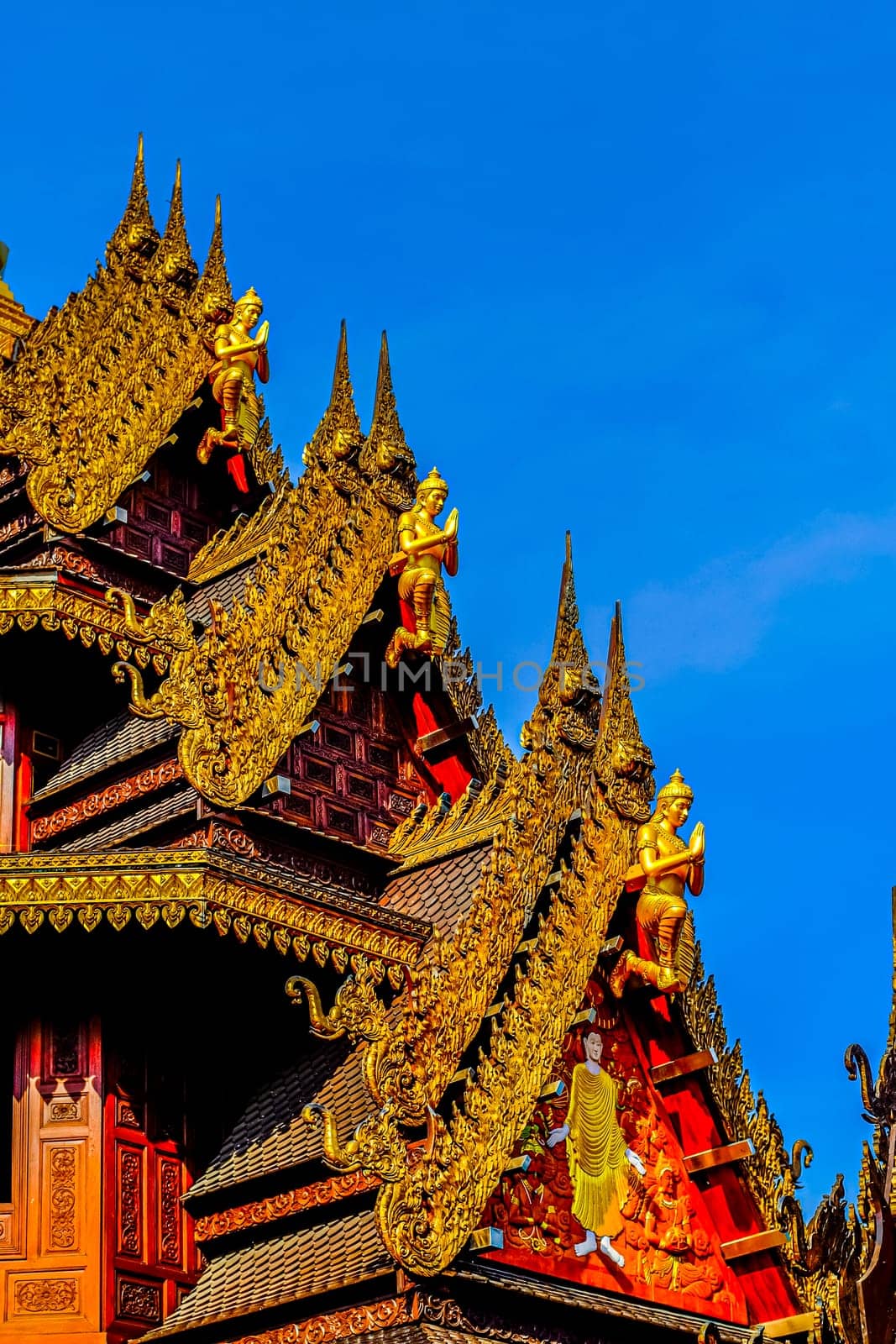 Traditional Thai Style Animal Gods Carved on Roof Decorations Against a Blue Sky by Petrichor