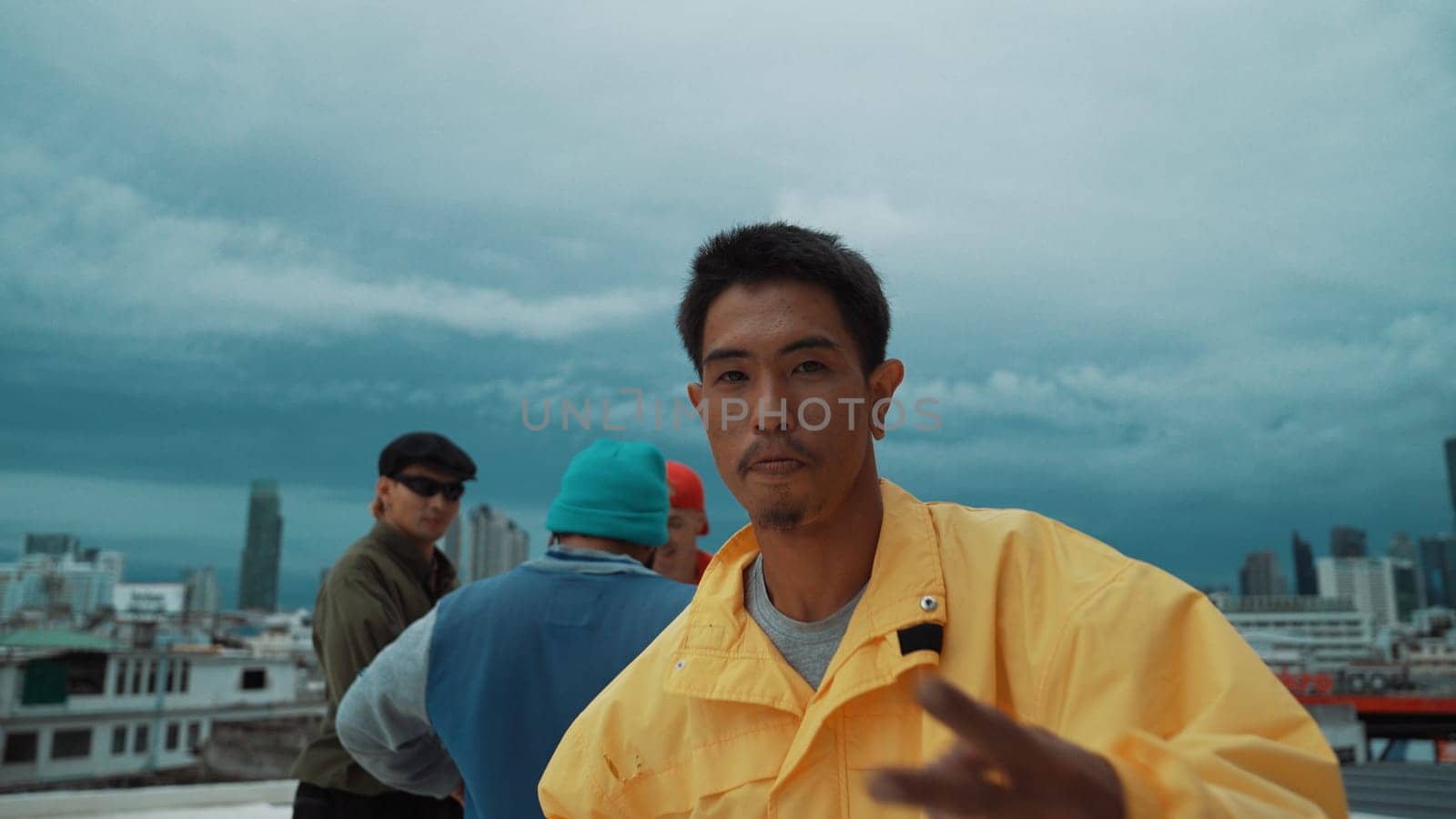 Hispanic hipster looking at camera surrounded by friend at rooftop. Endeavor. by biancoblue