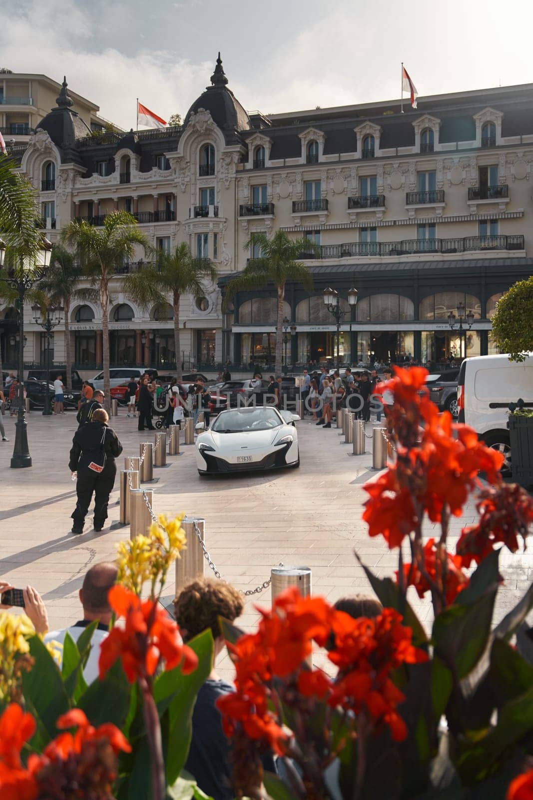 Monaco, Monte-Carlo, 22 October 2022: Square Casino Monte-Carlo at sunset, luxury cars, famous Hotel de Paris, wealth life, tourists take pictures of the landmark, pine trees, flowers. High quality photo