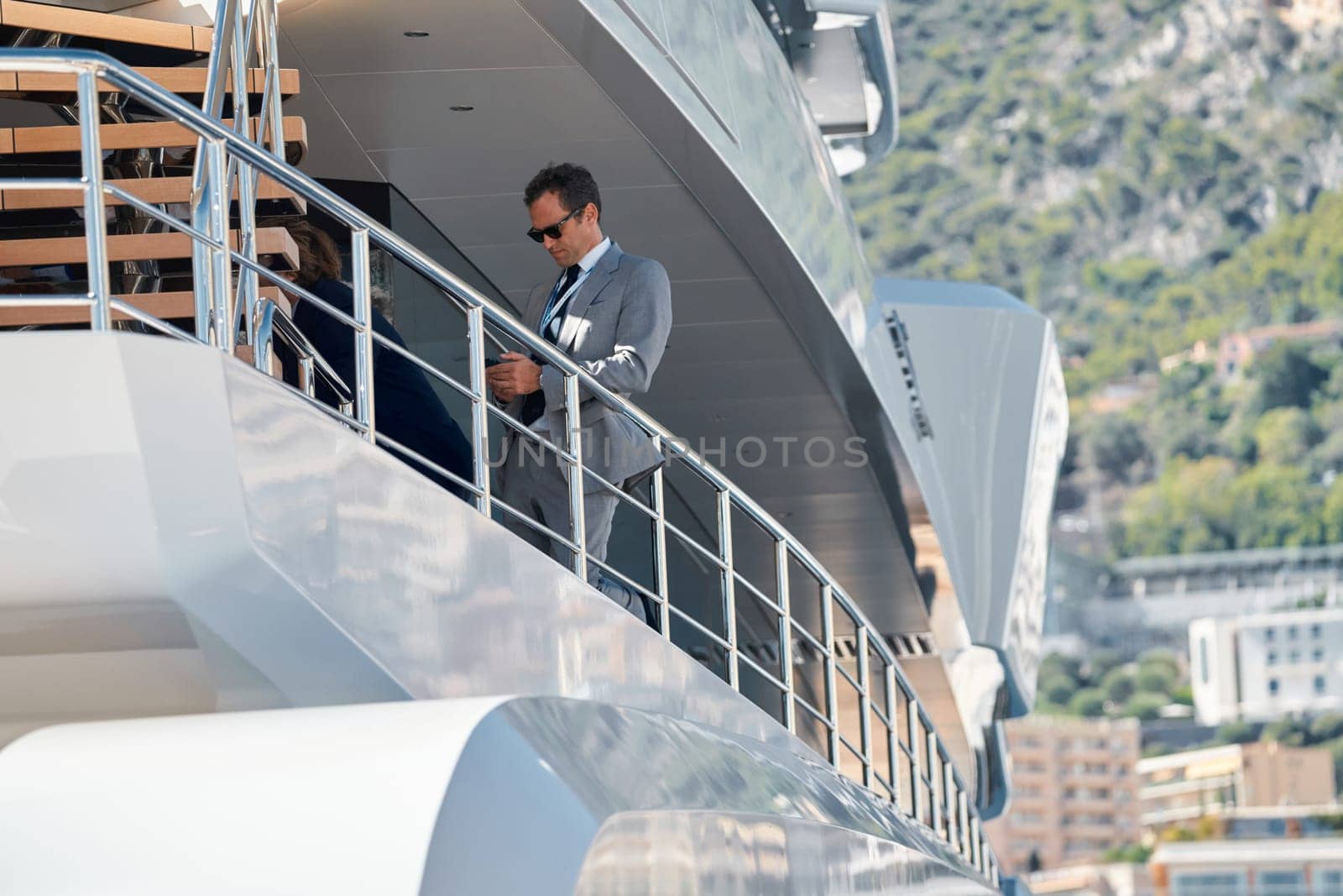 Monaco, Monte Carlo, 27 September 2022 - handsome man with smartphone on deck of mega yacht, Invited wealthy clients inspect megayachts at the largest fair exhibition in the world yacht show. High quality photo