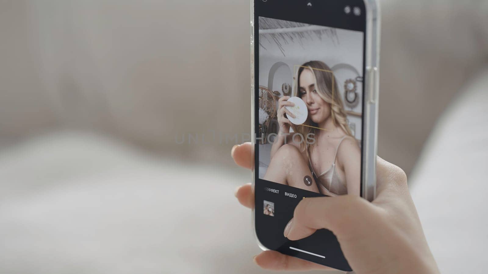 Close-up of beautiful young woman taking selfie. Action. Phone screen with selfie of young woman. Female blogger takes selfie with cosmetic product for advertising.