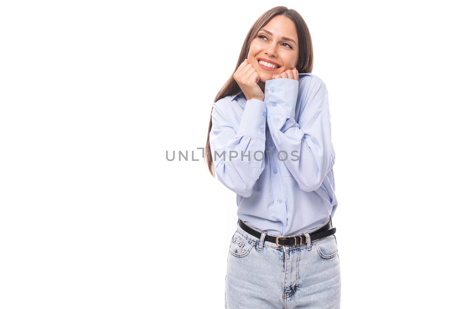 young smiling caucasian model woman with dark straight hair dressed in a blue blouse on a white background with copy space.