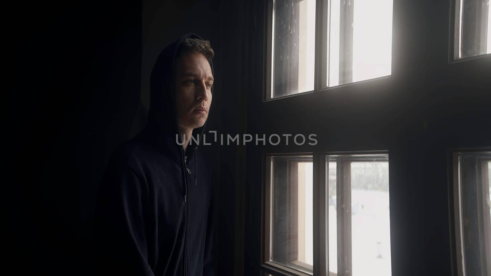Sad portrait of a man. Action. A handsome young man looking out the window indoors with a thoughtful look. High quality 4k footage