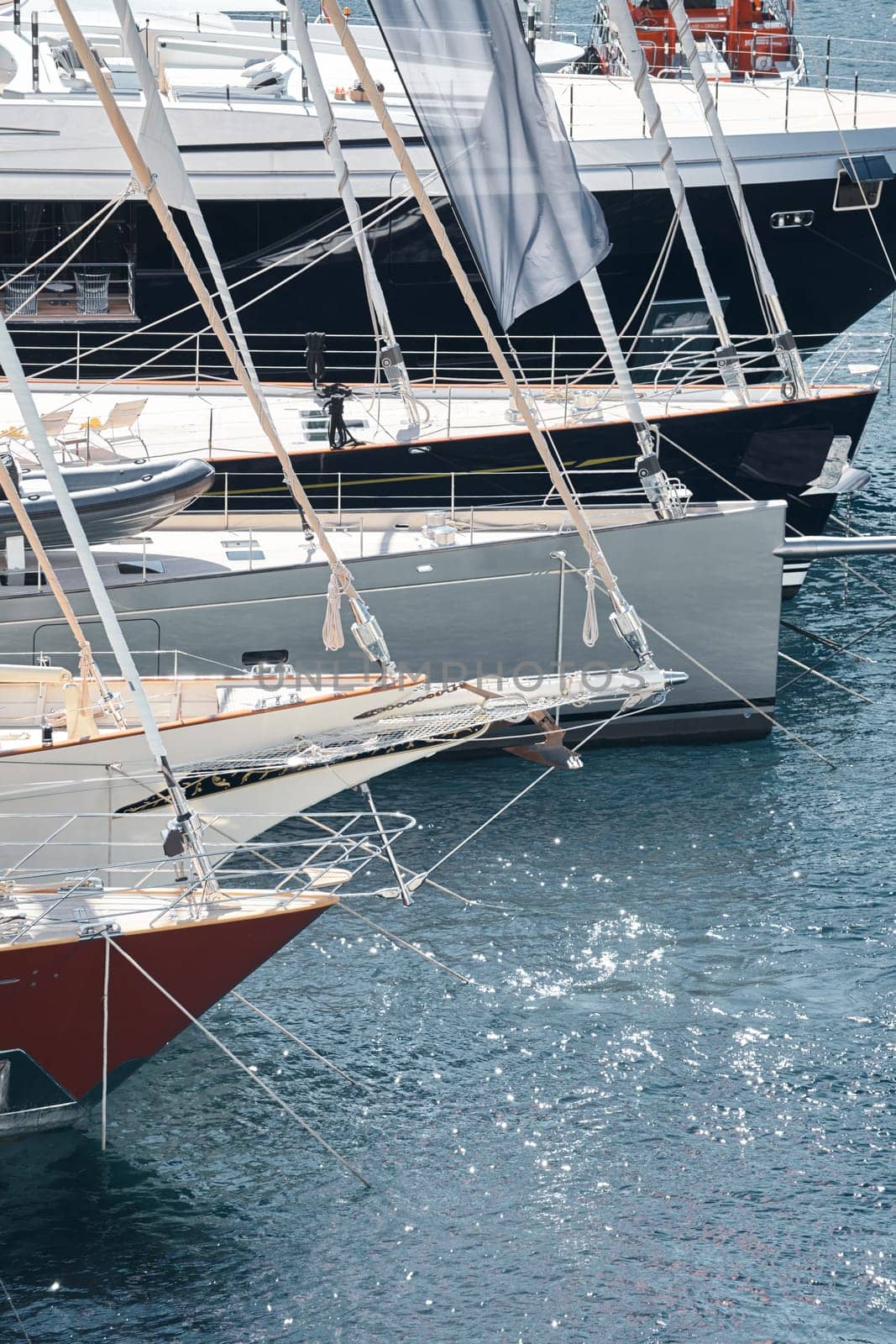 Sun glare on glossy board boats, azure water, tranquillity in port Hercules, bows of moored sailing boats at sunny day, megayachts, Monaco, Monte-Carlo. High quality photo