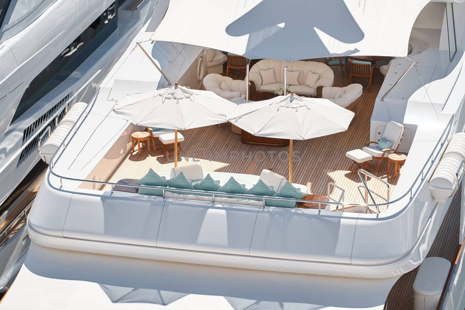 Close up footage of a relaxation area on the open teak deck of an expensive megayacht at sunny day, with awnings stretched over the deck to protect from the sun, wealth life, table and chairs. High quality photo