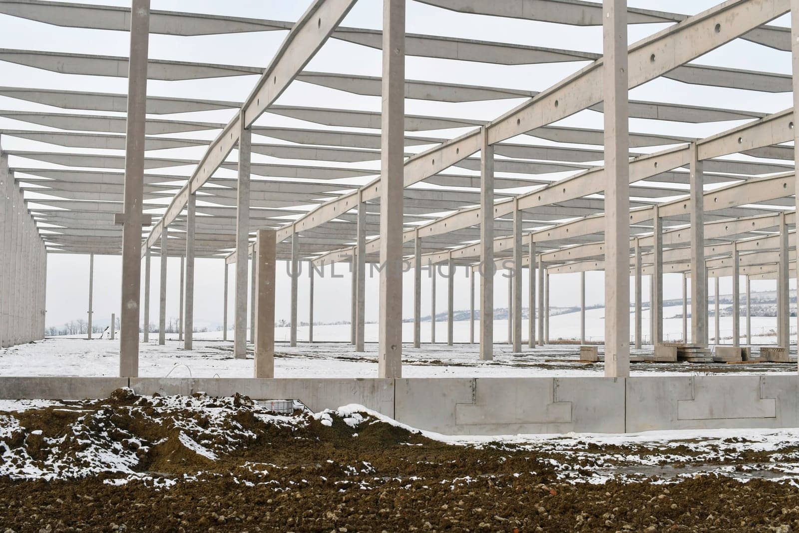 A dismantled factory hall in winter. Construction site during winter. The concept of the end of the building season and the completion of construction work before winter.