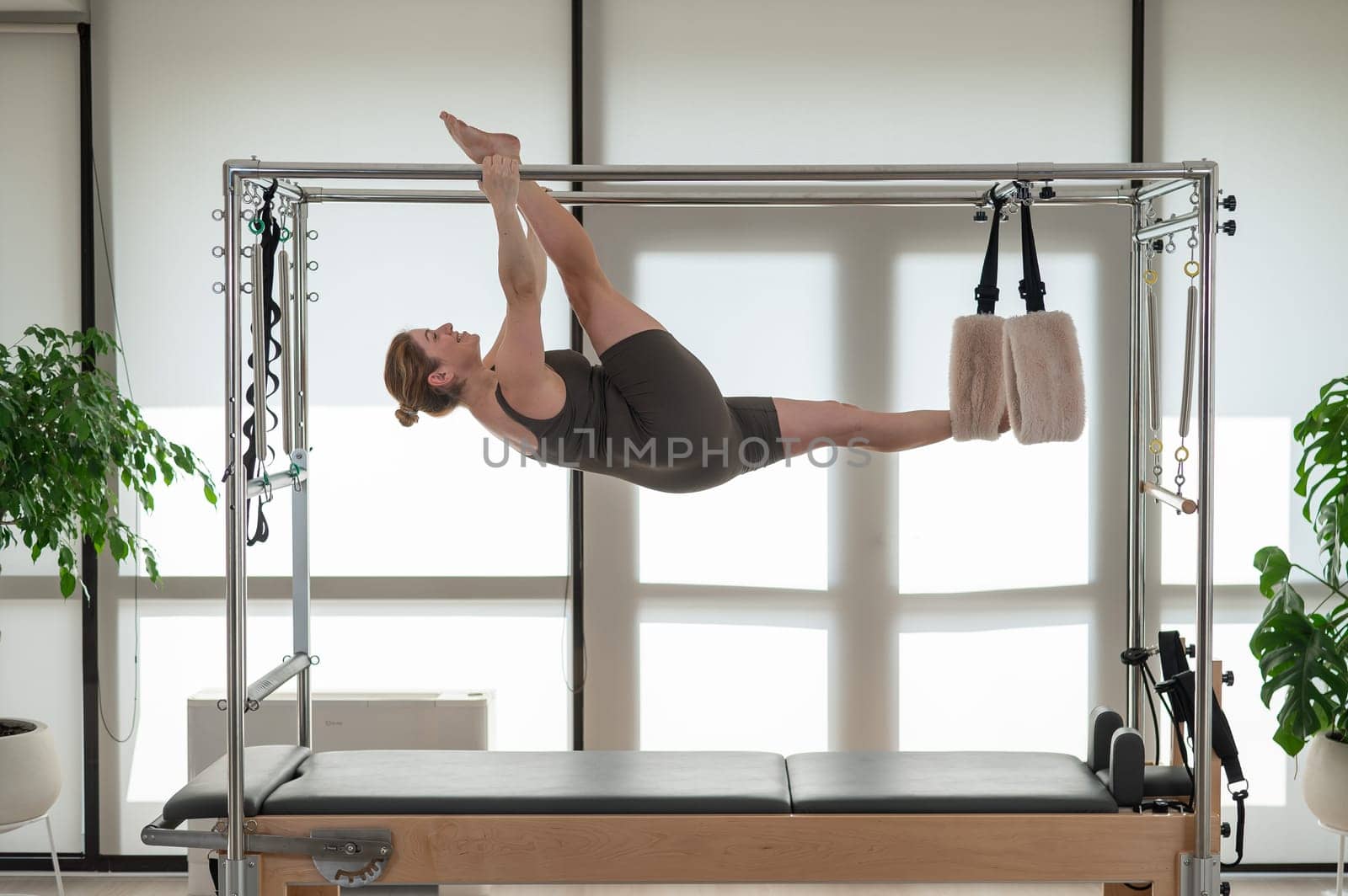 A pregnant woman is doing Pilates on a reformer. Aerial gymnastics