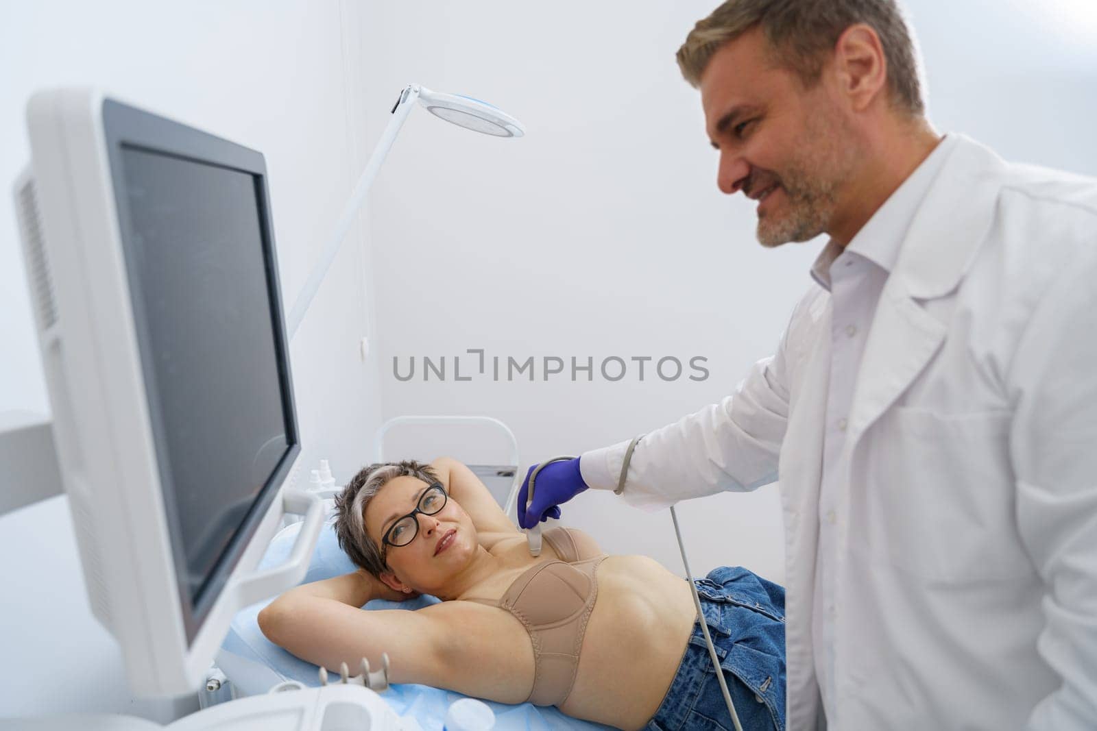 Mature woman during breast ultrasound examination at medical clinic. Healthcare concept by Yaroslav_astakhov