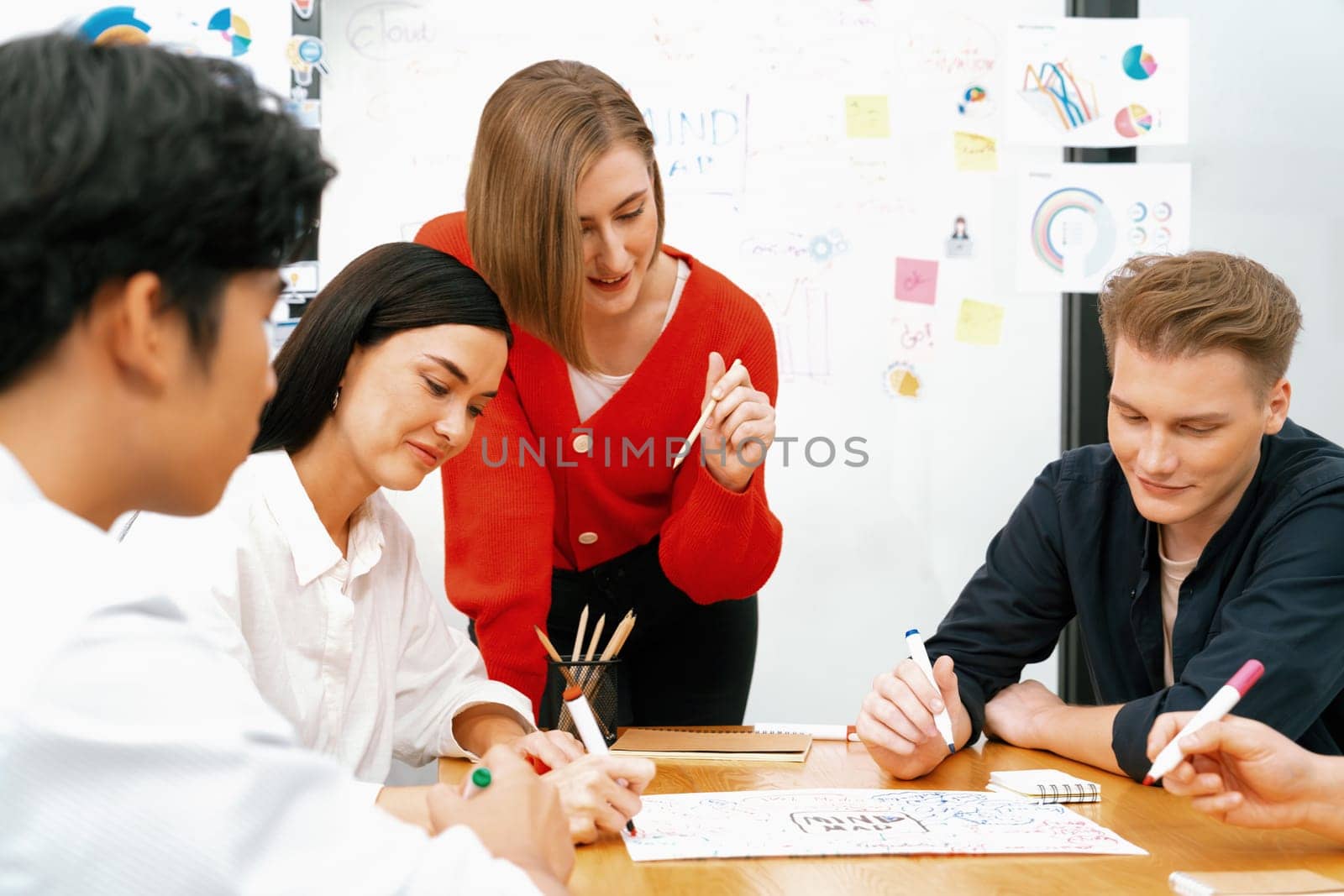 Happy cooperative multi-ethnic business group brainstorming discussion about marketing plan by using mind map in front of glass board with colorful sticky notes at meeting room. Immaculate.