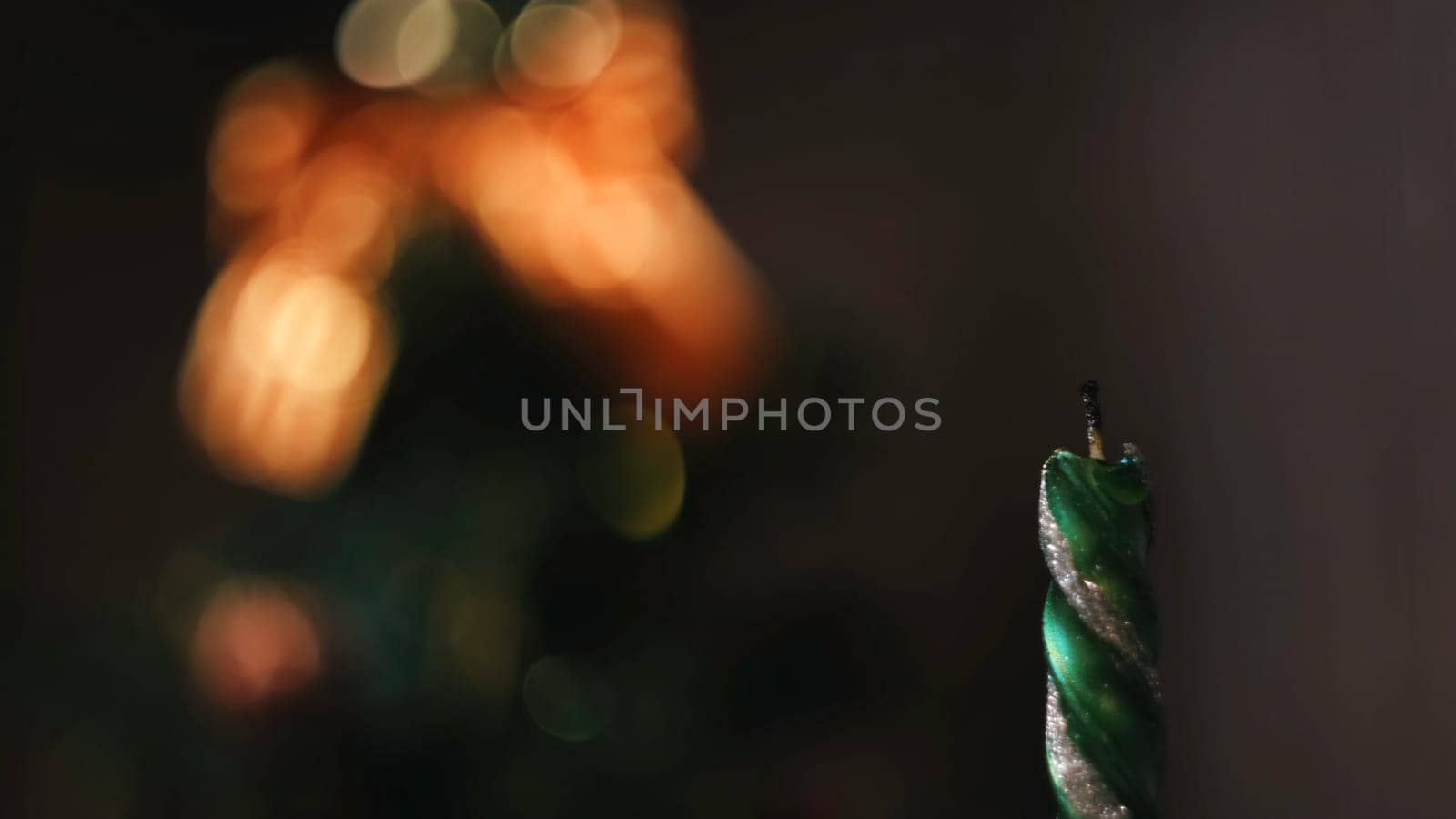 Close-up of Christmas extinct candle against the blurred Christmas tree silhouette with lights and decorations. Christmas mood